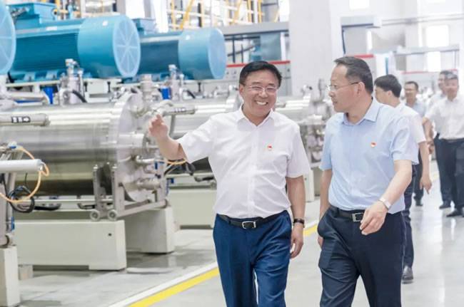 国轩高科董事长李缜(左)陪同庐江县委书记许华为(右)参观国轩科宏一期正极材料产线
